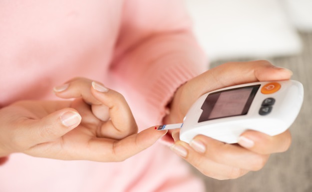 femeie testeaza glicemia cu aparatul pentru a face insulina