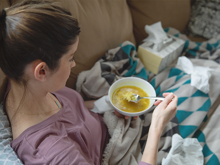 femeie mananca supa de pui in pat